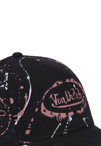 Gorra negra con diseño de pintura salpicada en blanco y rosa, con un logo circular y tachuelas. Forma estructurada con una corona redondeada.