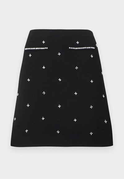 Μαύρη φούστα σε γραμμή Α με μικρές λευκές πέρλες ως διακοσμητικά και δύο ψεύτικες τσέπες μπροστά περιμετρικά διακοσμημένες με πέρλες.