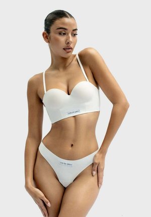 White bralette and matching thong set, smooth texture, molded cups, adjustable straps, logo detailing at the waistband, minimalistic design.