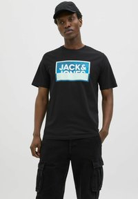 Sort bomulds T-shirt med et rektangulært bl�åt grafisk design med "JACK & JONES" i hvid. Korte ærmer og rund hals.