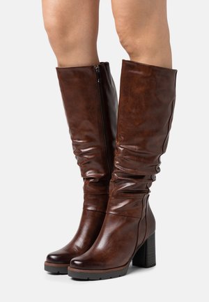 Brązowe, sztuczne skórzane kozaki za kolano o luźnym kroju, zwężającym się nosku, grubym obcasie i bocznym zamku błyskawicznym. Gładka tekstura z delikatnym połyskiem.