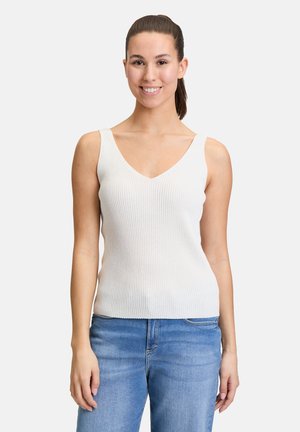 White ribbed tank top with a V-neckline and wide straps, paired with light blue denim jeans. Smooth texture, fitted design.