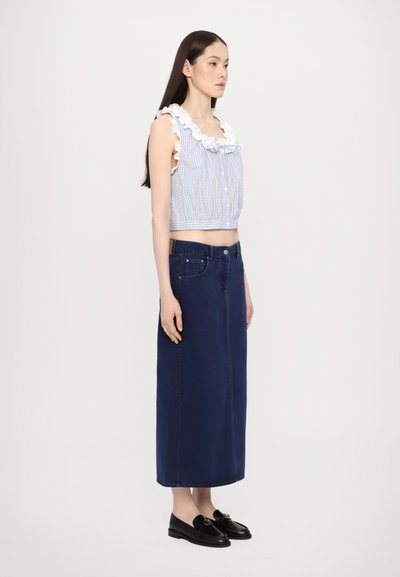 Blauw en wit geruit crop top met een gerimpelde halslijn, gecombineerd met een lange marineblauwe denimrok en zwarte loafers met gouden accenten.