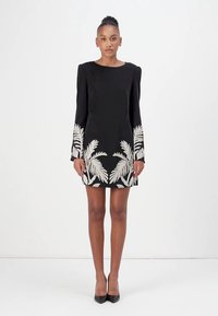 Black dress with long sleeves, featuring cream palm leaf embroidery at the hem. The fabric is smooth, and the design includes structured shoulders.