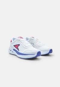 Baskets de sport blanches avec une texture lisse, ornées d'accents rouges et bleus, à lacets à l'avant et avec une languette rembourrée pour le confort.