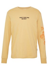Langärmliges, hellgelbes T-Shirt mit schwarzem Text "VERTRAUE DEINEN EIGENEN INSTINKTEN" und Design einer orangefarbenen Schlange auf dem rechten Ärmel. Baumwollstoff.
