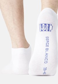 Chaussettes blanches mi-mollet avec un bord côtelé, texte bleu "SERGE BLANC" et taille "33-34" au niveau du talon, fabriquées en tissu doux.