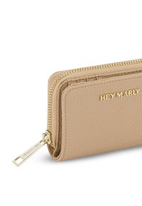 Beige leren portemonnee met een textuurafwerking, een gouden rits en de verhoogde merknaam "HEY MARLY" aan de voorkant. Voorzien van een ritssluiting.