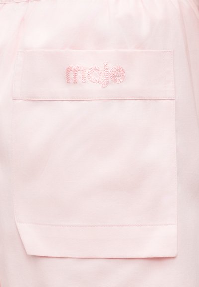 Ανοιχτό ροζ υφασμάτινη τσέπη με κεντημένο το "maje" με νήμα στο ίδιο ροζ χρώμα στο άνω κέντρο της τσέπης.