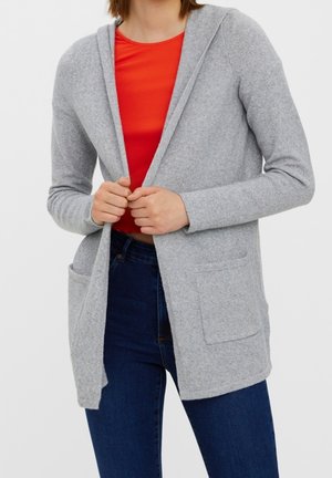 Cardigan grigio chiaro con cappuccio, dotato di due tasche frontali. Il tessuto sembra morbido e texture, indossato sopra una maglietta rossa.