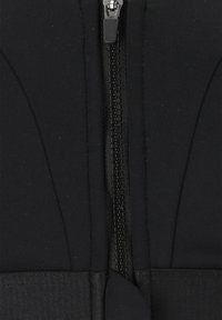 Svart atletisk topp med en framträdande dragkedja, slät yta och strukturerad paneldesign. Har en stilren, minimalistisk look.