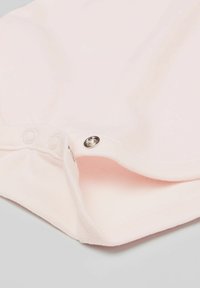 Jasnoróżowa tkanina o miękkiej teksturze, z zapięciem na zatrzask. Design zawiera zaokrąglony dół i ribbowane akcenty.