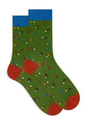 Grüne Socken mit blauen Knöchel-Bündchen, die ein Muster aus bunten Flaggen und Golfbällen zeigen. Orangefarbene Akzente an Zehen und Ferse. Sanfte Textur.