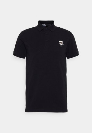 Svart bomullspikétröja med klassisk krage, tre knappar och en grafisk logotyp på vänster bröst. Kortärmad med normal passform.