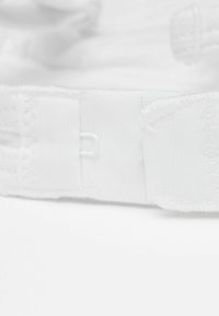 White fabric strap with textured surface, featuring adjustable hardware and clean stitching, shown at an angle on a white background.