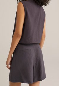 Ärmlös mörkgrå skräddarsydd topp i kombination med matchande högmidjade shorts, med sidfickor och en texturerad väv.