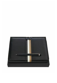 Pochette noire en cuir avec fermeture éclair, ornée de rayures verticales beiges et blanches, accompagnée d'un stylo noir élégant, présentée sur une boîte noire.