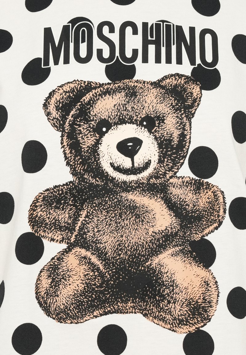 Moschino t-shirt met een bruine teddybeer grafiek, zwarte stippen op een witte achtergrond, met vet zwart lettertype boven de beer.