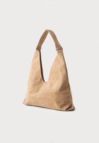 Blød tan læder hobo taske med en bred skulderrem, dybt udskåret åbning og glat tekstur. Minimalistisk design uden synligt hardware.