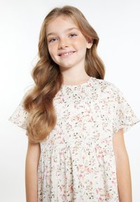 Blumenkleid mit hellem Creme-Hintergrund, das pinke und grüne Muster aufweist, kurze Ärmel und eine geraffte Taille hat. Glattes, leichtes Gewebe.