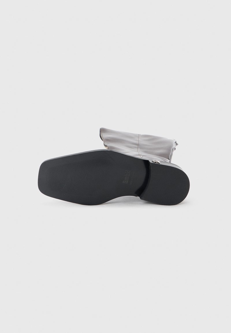 Botte de cheville grise avec une texture douce et brillante, dotée d'une semelle noire texturée et d'un léger pli en haut, soulignant une silhouette arrondie.