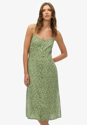 Grünes, blumiges Midikleid mit dünnen Trägern, einer durchgehenden Knopfleiste und einer fließenden Textur, die mit weißen Blumenmustern versehen ist.
