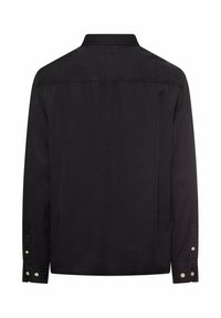 Chemise noire à manches longues en coton doux, avec un col classique, des poignets à boutons et un ourlet droit. Design minimaliste sans motifs.