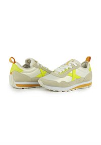 Baskets beige avec des accents jaunes, en matériaux daim et mesh, design à lacets et un onglet de talon orange contrastant. Semelle en caoutchouc avec un profil texturé.