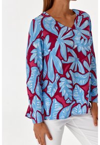 Bluzka z długim rękawem w kolorze fuksji z niebieskim nadrukiem tropikalnych liści, z dekoltem w szpic i miękką, gładką fakturą.