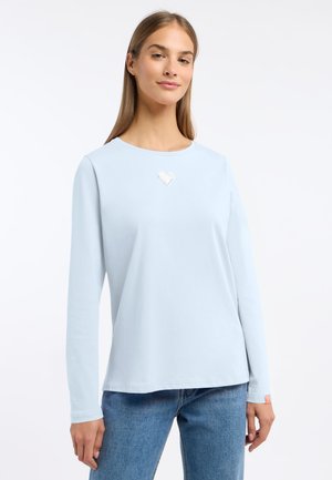 Lichtblauw langekorte t-shirt van zachte stof met een klein hartdetail op de borst. Relaxte pasvorm met een ronde halslijn en omgevouwen mouwen.