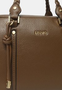 Borsa a mano in pelle marrone con superficie texturizzata, manico intrecciato e accessori placcati in oro con il nome del marchio "LIU JO" impresso sul davanti.