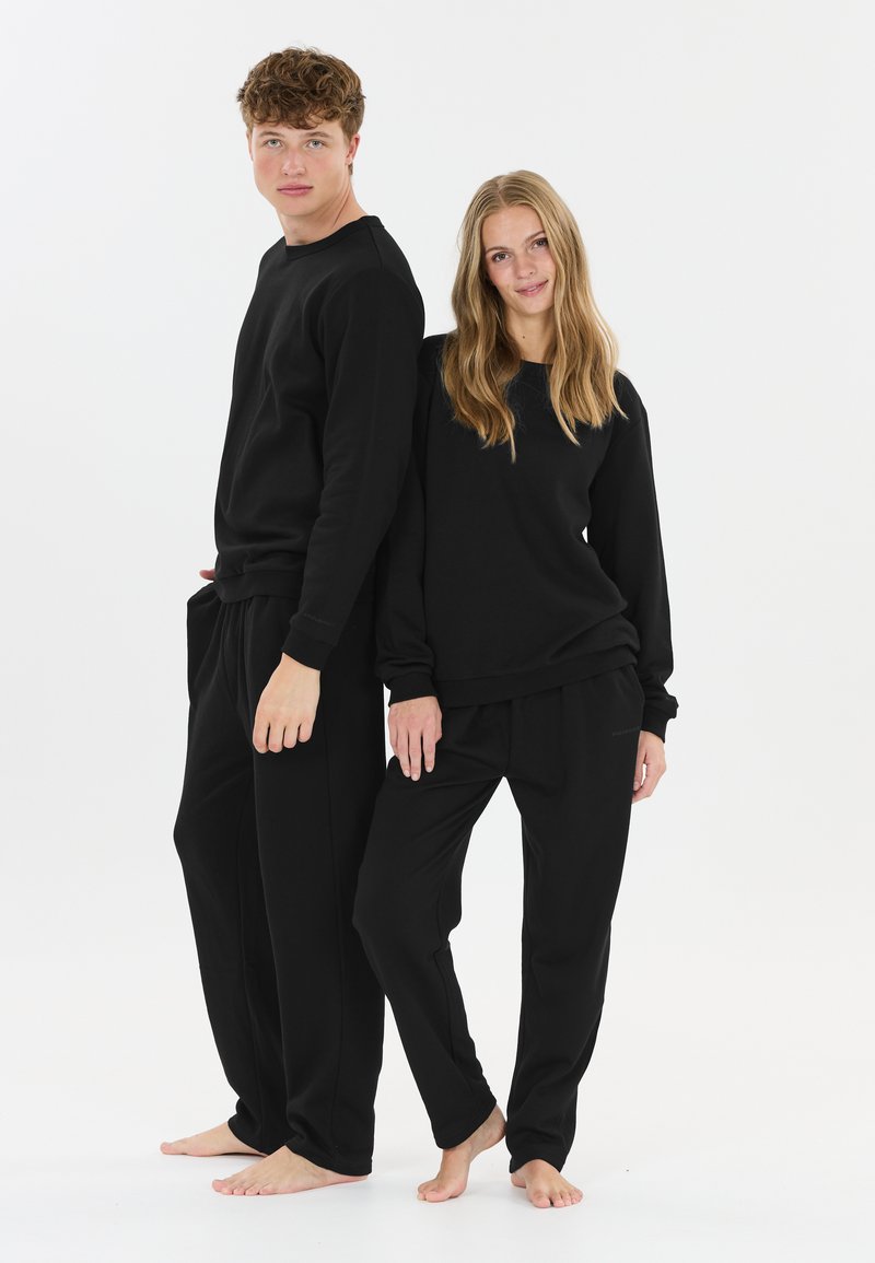 Zwarte loungewearset met een sweatshirt met ronde hals en relaxte broek. Gemaakt van zachte stof, met geribde manchetten en tailleband.