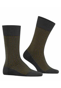 Chaussettes noires avec un poignet côtelé, décorées d'un motif de points orange et jaune, design fuselé et texture lisse.