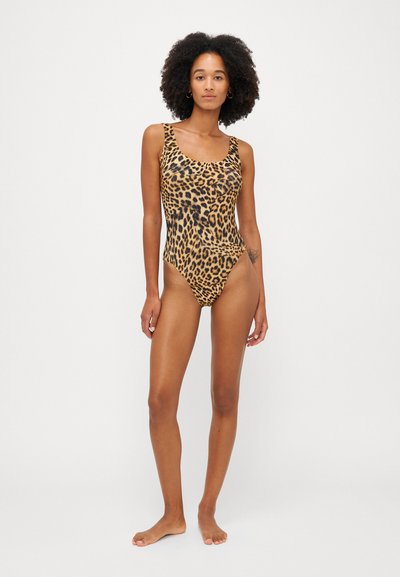 Bañador de una pieza con estampado de leopardo, escote en forma de barco, tirantes gruesos, piernas de corte alto y una textura de tela suave y elástica.