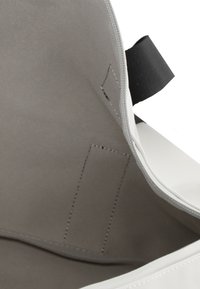 White tote bag with a smooth exterior, gray fabric lining, and contrasting stitching. Features an inner pocket and a sturdy black strap.