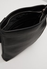 Borsa in pelle nera con superficie testurizzata, con apertura a zip e interno in tessuto scuro, progettata per organizzare gli oggetti con più scomparti.