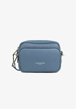 Sac bandoulière rectangulaire en cuir bleu avec poche zippée à l'avant et ferrures argentées, marqué "Lancaster Paris" sur le devant.