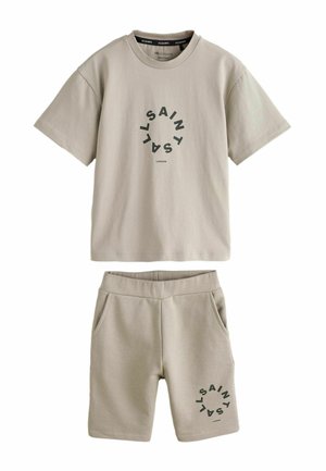 Beiges Baumwoll-T-Shirt mit rundem Grafikdruck und passenden Shorts. Beide Teile haben eine lockere Passform und einen elastischen Bund mit Taschen.