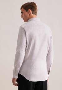 Geruite shirt in lichte stof met een klassieke kraag, voorzien van kleine vierkanten in blauw en bruin, lange mouwen met knoopdetails.