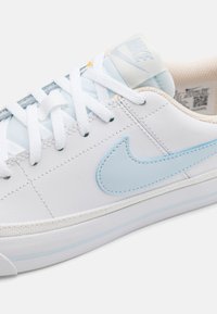 Baskets blanches avec des accents bleu clair, dotées d'un dessus en cuir lisse, d'un design à lacets et d'une semelle en caoutchouc avec une bande bleu clair.