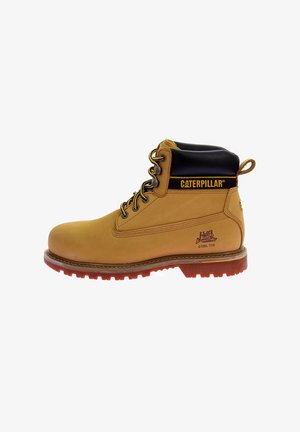 Botte de travail en cuir tan avec un col noir, protection à embout en acier, semelle en caoutchouc brun, accents oranges et détail du logo sur le côté.