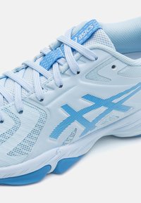 Světle modrá sportovní bota s síťovinovým svrškem, texturovanými pruhy a polstrovanou podešví. Šňůrky jsou modré a na jazyku je štítek s logem.