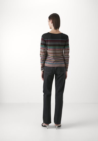 Top de manga larga a rayas con colores variados, con un escote redondeado. Combinado con vaqueros negros de cintura alta y sandalias de tacón fino.