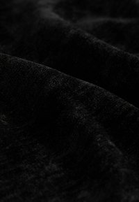 Sort fløjlstof med en blød tekstur, der har en glat overflade, som fanger lyset og skaber subtile variationer i nuance og dybde.