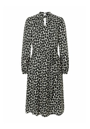 Zwart-wit stippenjurk met lange mouwen, sleutelgat halslijn, getailleerde taille en een gestrikt riem in de taille. Zachte stoffen textuur.