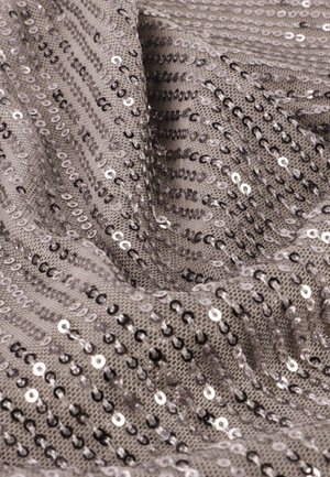 Tissu argent-gris avec des rangées verticales de sequins brillants, créant une surface texturée et scintillante. Un matériau de fond doux et tissé est visible.