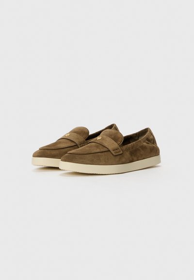 Braune Wildleder Slip-On-Schuhe mit niedrigem Profil, runder Zehenpartie und einer cremefarbenen Gummisohle. Mit einem dekorativen Riemen mit Logodetail.