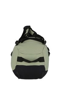 Compact bag in light green fabric with black accents. Features a sturdy handle and adjustable straps for versatile carrying options.