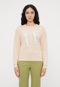 Felpa pesca con logo bianco "AX" e testo "ARMANI EXCHANGE", con scollo rotondo e maniche lunghe. Abbinata a pantaloni verdi.