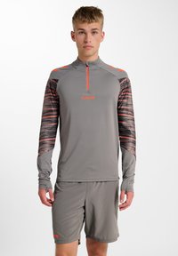 Graues Sportoberteil mit einem viertel Reißverschluss, langen Ärmeln und lebhaften orangen Akzenten; gemusterte Ärmel mit einem strukturierten Design.